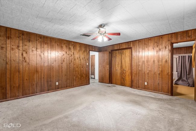 Unfurnished bedroom with carpet floors, wooden walls, a closet, and a ceiling fan | Image 18