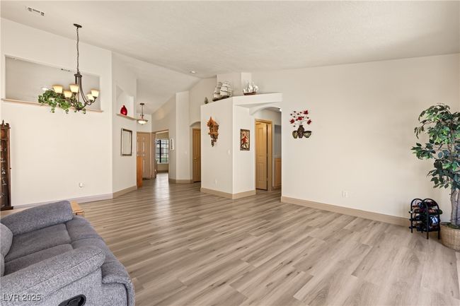Living area featuring light wood finished floors, arched walkways, a chandelier, and high vaulted ceiling | Image 20