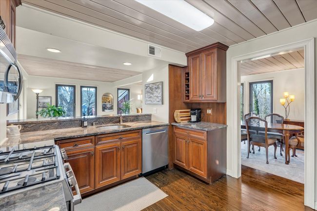 Kitchen featuring dark hardwood / wood-style floors, sink, dark stone counters, wood ceiling, and stainless steel appliances | Image 10
