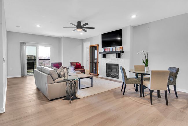 Living room featuring a ceiling fan, baseboards, a large fireplace, and light wood-style floors | Image 8