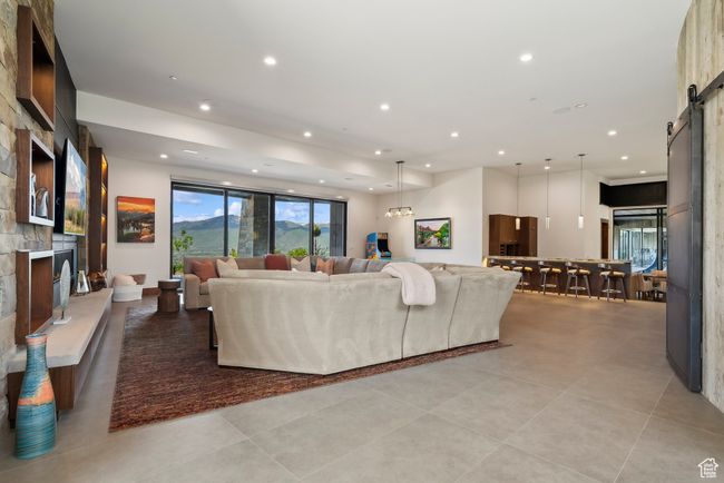 Living area featuring a barn door, recessed lighting, a large fireplace, and light tile patterned floors | Image 47