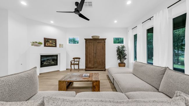 Living room featuring recessed lighting, light wood-type flooring, a glass covered fireplace, and ceiling fan | Image 12