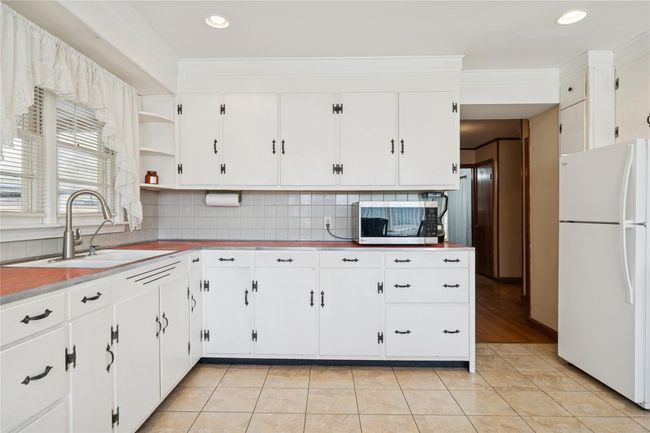 Kitchen featuring a sink, ornamental molding, freestanding refrigerator, light tile patterned flooring, and open shelves | Image 21