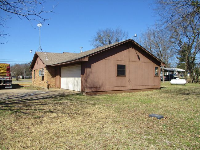 View of side of home with a garage, a yard, driveway, and brick siding | Image 19