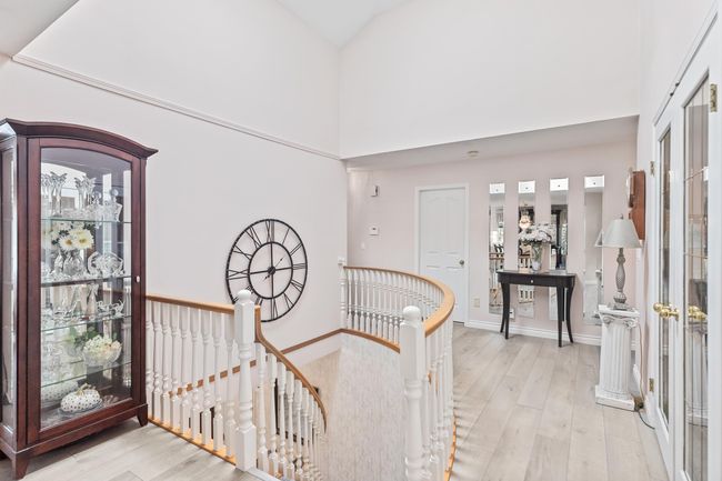 Hall with an upstairs landing, light wood-style floors, and a towering ceiling | Image 4