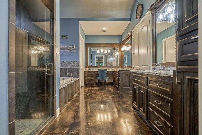 The primary bath offers a luxurious retreat with two separate vanities, each providing ample storage. A jetted soaking tub, separate glass-enclosed shower, private toilet room, and a spacious walk-in closet complete this well-appointed space. | Image 29