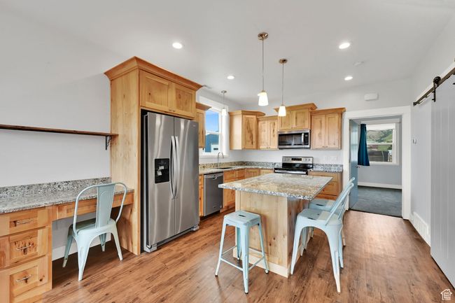 Kitchen with appliances with stainless steel finishes, a barn door, a breakfast bar area, a kitchen island, and plenty of natural light | Image 50