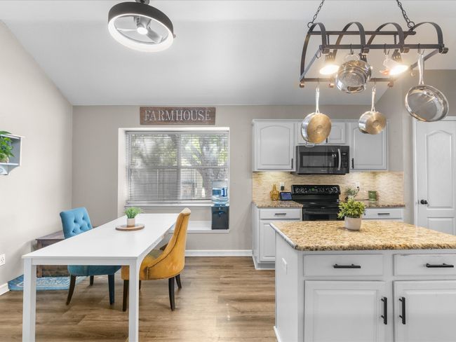 Kitchen featuring stainless steel microwave, electric range, light wood-type flooring, decorative backsplash, and white cabinetry | Image 9
