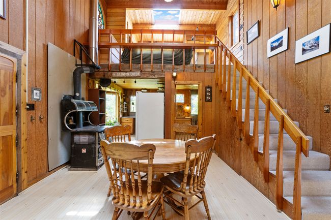 Dining space featuring wooden walls, light wood-style flooring, and stairs | Image 16