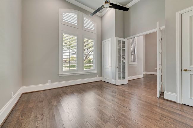 Unfurnished room with baseboards, a towering ceiling, a ceiling fan, wood finished floors, and ornamental molding | Image 7