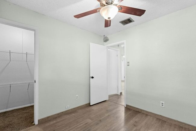 Unfurnished bedroom with wood finished floors, a spacious closet, a ceiling fan, and a textured ceiling | Image 24