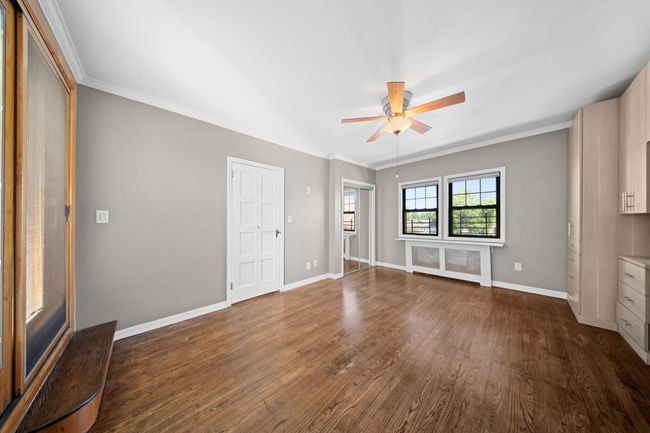 Unfurnished living room featuring dark wood-style floors, ceiling fan, baseboards, and crown molding | Image 23