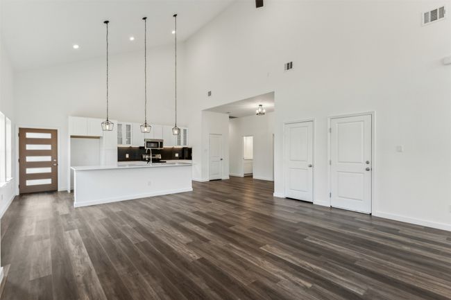 Unfurnished living room with high vaulted ceiling, dark wood-style floors, and recessed lighting | Image 15