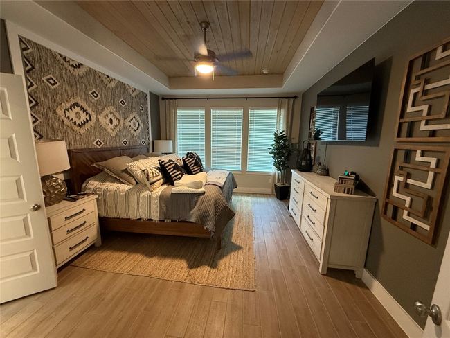 Bedroom featuring wooden ceiling, light wood finished floors, baseboards, a tray ceiling, and ceiling fan | Image 13