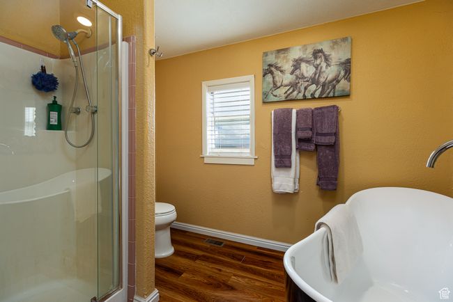 Bathroom featuring hardwood / wood-style flooring, toilet, and a shower with door | Image 15