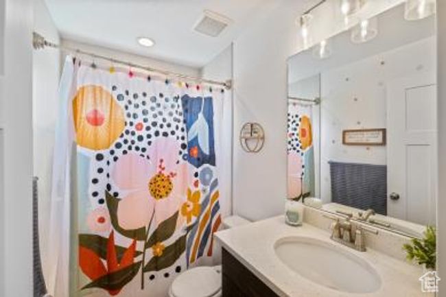 Full bath featuring a shower with curtain, vanity, and toilet | Image 27