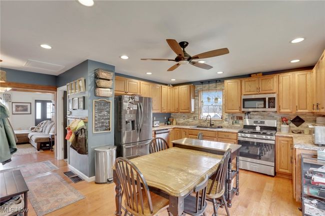 Kitchen with appliances with stainless steel finishes, a ceiling fan, decorative backsplash, light wood-type flooring, and recessed lighting | Image 11