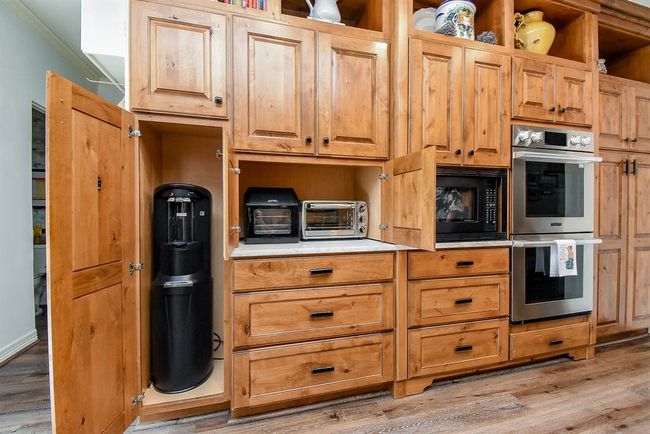 Back bank of cabinets opens to offer water cooler storage and garage appliance on the other end, is pull out pantry storage! | Image 20