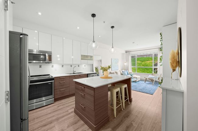 Kitchen featuring light wood-style flooring, modern cabinets, a sink, open floor plan, and appliances with stainless steel finishes | Image 12