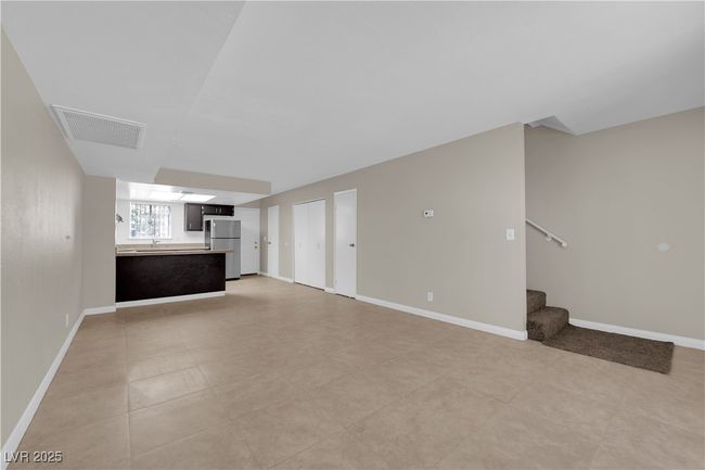 Unfurnished living room with stairway, baseboards, and a sink | Image 4