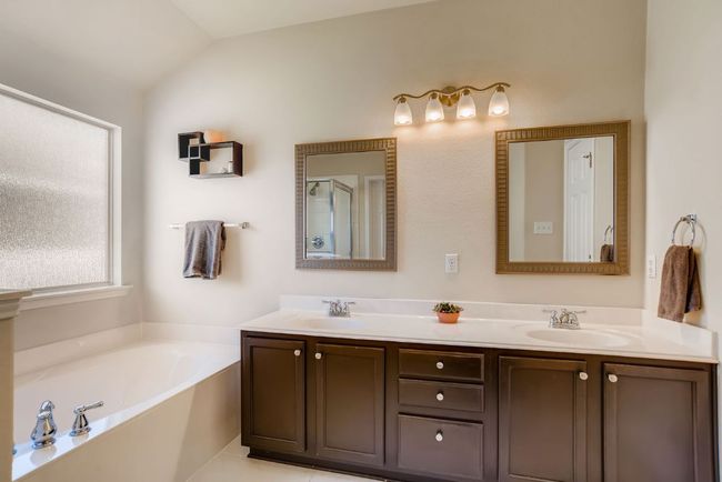 Bathroom with double vanity, lofted ceiling, and a bath | Image 18