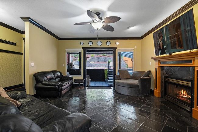 Living area featuring a premium fireplace, ceiling fan, ornamental molding, baseboards, and stone finish flooring | Image 18