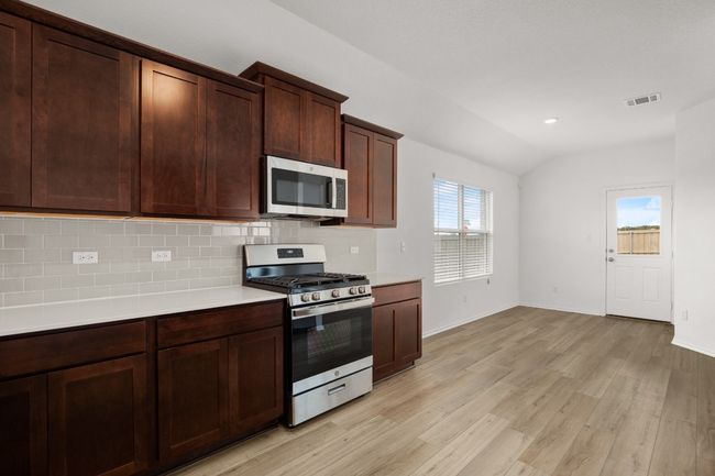Kitchen with appliances with stainless steel finishes, light countertops, decorative backsplash, light wood finished floors, and vaulted ceiling | Image 11