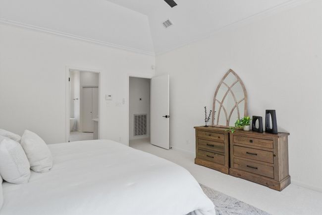 Bedroom with light colored carpet, a towering ceiling, ensuite bathroom, a ceiling fan, and baseboards | Image 18