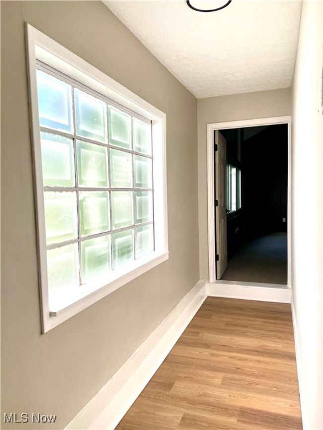 Hallway featuring light wood-style flooring, healthy amount of natural light, and a textured ceiling | Image 12