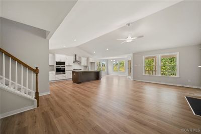 Unfurnished living room with sink, light hardwood / wood-style flooring, lofted ceiling, and ceiling fan with notable chandelier | Image 3