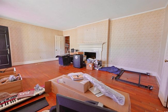 Living area featuring wallpapered walls, wood-type flooring, ornamental molding, and a fireplace | Image 17