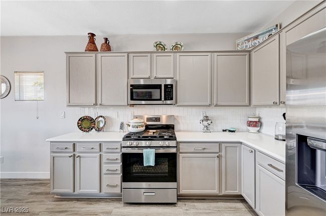 Kitchen with stainless steel appliances, tasteful backsplash, light countertops, and light wood-type flooring | Image 6