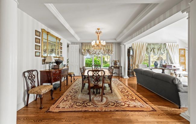Dining area with a chandelier, a tray ceiling, wood finished floors, and crown molding | Image 12