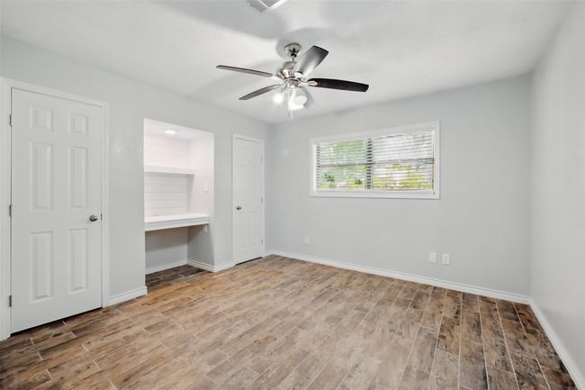 Light-filled and versatile, the secondary bedroom offers a custom desk nook with shelving, a ceiling fan, and flexible layouts to fit your needs. | Image 25