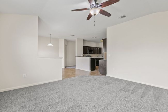Unfurnished living room featuring light carpet, a ceiling fan, and baseboards | Image 25