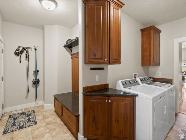 Mud Room entrance from garage and Laundry area with cabinet space, washer and dryer, baseboards, a textured ceiling, and light tile patterned floors | Image 14