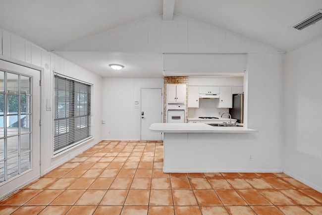 Kitchen with visible vents, white cabinets, light tile patterned floors, lofted ceiling with beams, and light countertops | Image 9