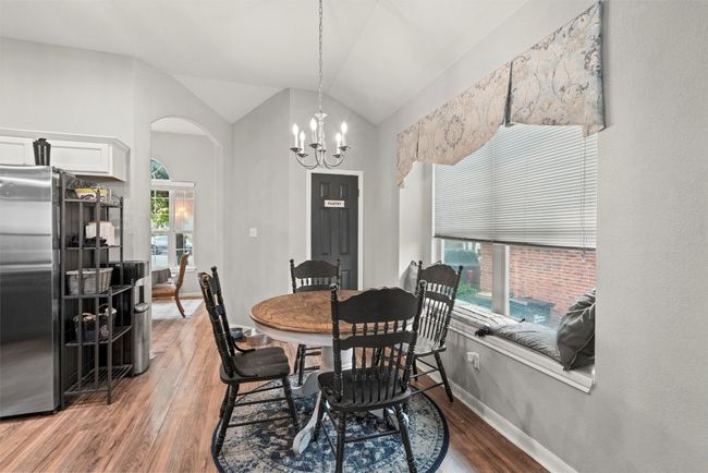 Dining area with arched walkways, baseboards, vaulted ceiling, and wood finished floors | Image 7