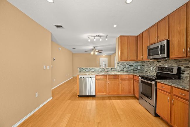 Kitchen featuring appliances with stainless steel finishes, a sink, light wood-type flooring, tasteful backsplash, and recessed lighting | Image 9