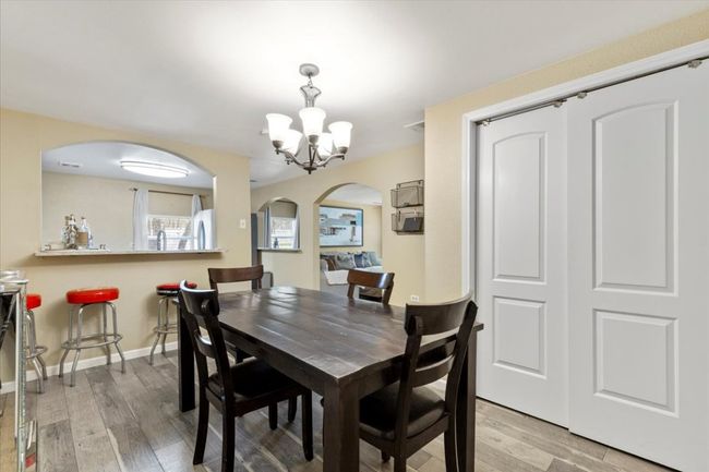 Dining area with light wood finished floors, baseboards, arched walkways, and a chandelier | Image 11