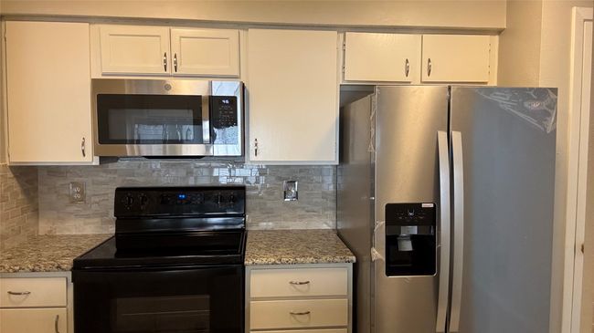 Kitchen featuring stainless steel appliances, backsplash, and white cabinets | Image 5