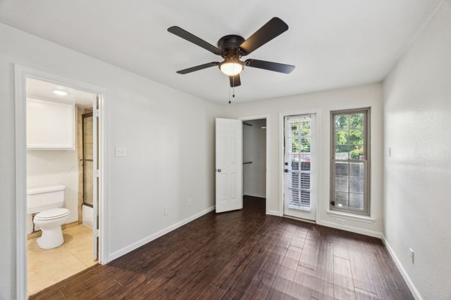 Spacious bedroom with dark wood-style flooring, access to outside private patio, ensuite bath, and baseboards | Image 10