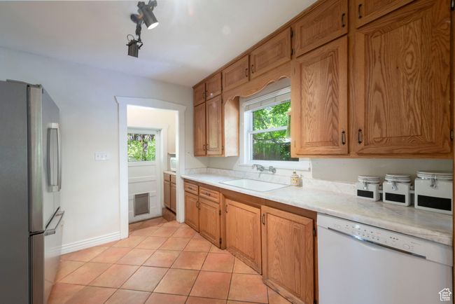 Kitchen featuring freestanding refrigerator, dishwasher, light countertops, and healthy amount of natural light | Image 11