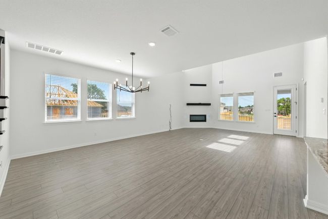 Unfurnished living room with a chandelier, healthy amount of natural light, light wood-type flooring, and recessed lighting | Image 8