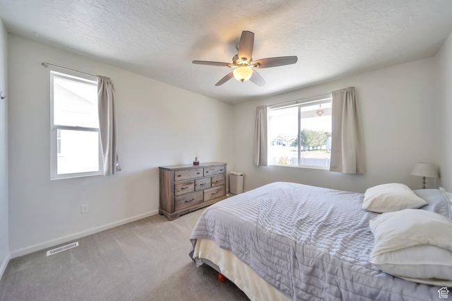 Carpeted bedroom featuring baseboards, visible vents, a textured ceiling, and ceiling fan | Image 13