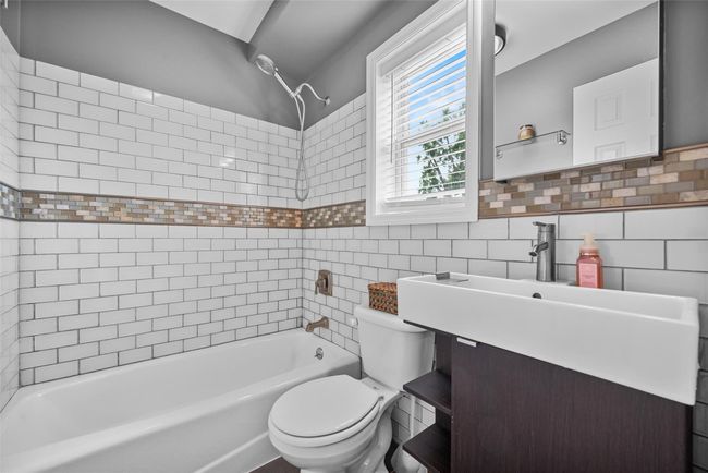 Full bathroom featuring shower combination, tile walls, and vanity | Image 23