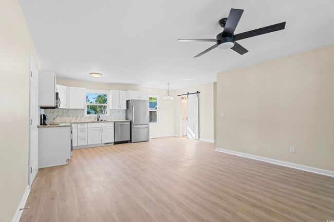 Unfurnished living room with a barn door, light wood finished floors, and ceiling fan | Image 16