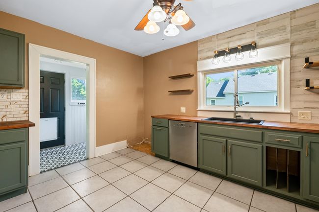 Kitchen with green cabinetry, butcher block counters, stainless steel dishwasher, and a sink | Image 11