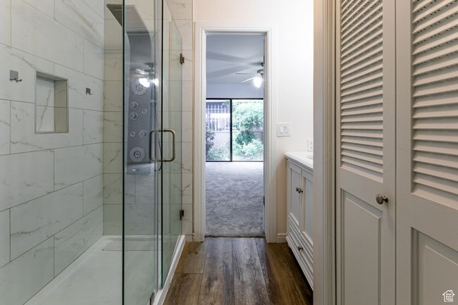 Bathroom featuring ceiling fan, wood finished floors, a shower stall, and vanity | Image 19
