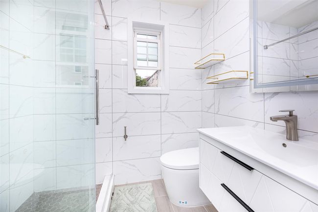 Full bathroom featuring tile walls, vanity, a shower stall, and toilet | Image 17